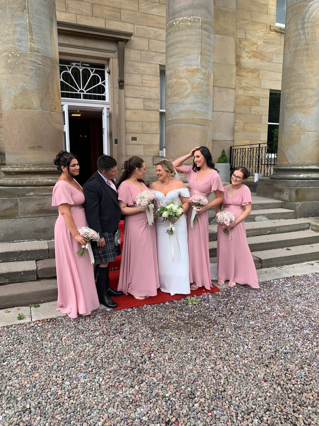 Bride in an off-the-shoulder crepe wedding gown with bridesmaids at a Scottish wedding