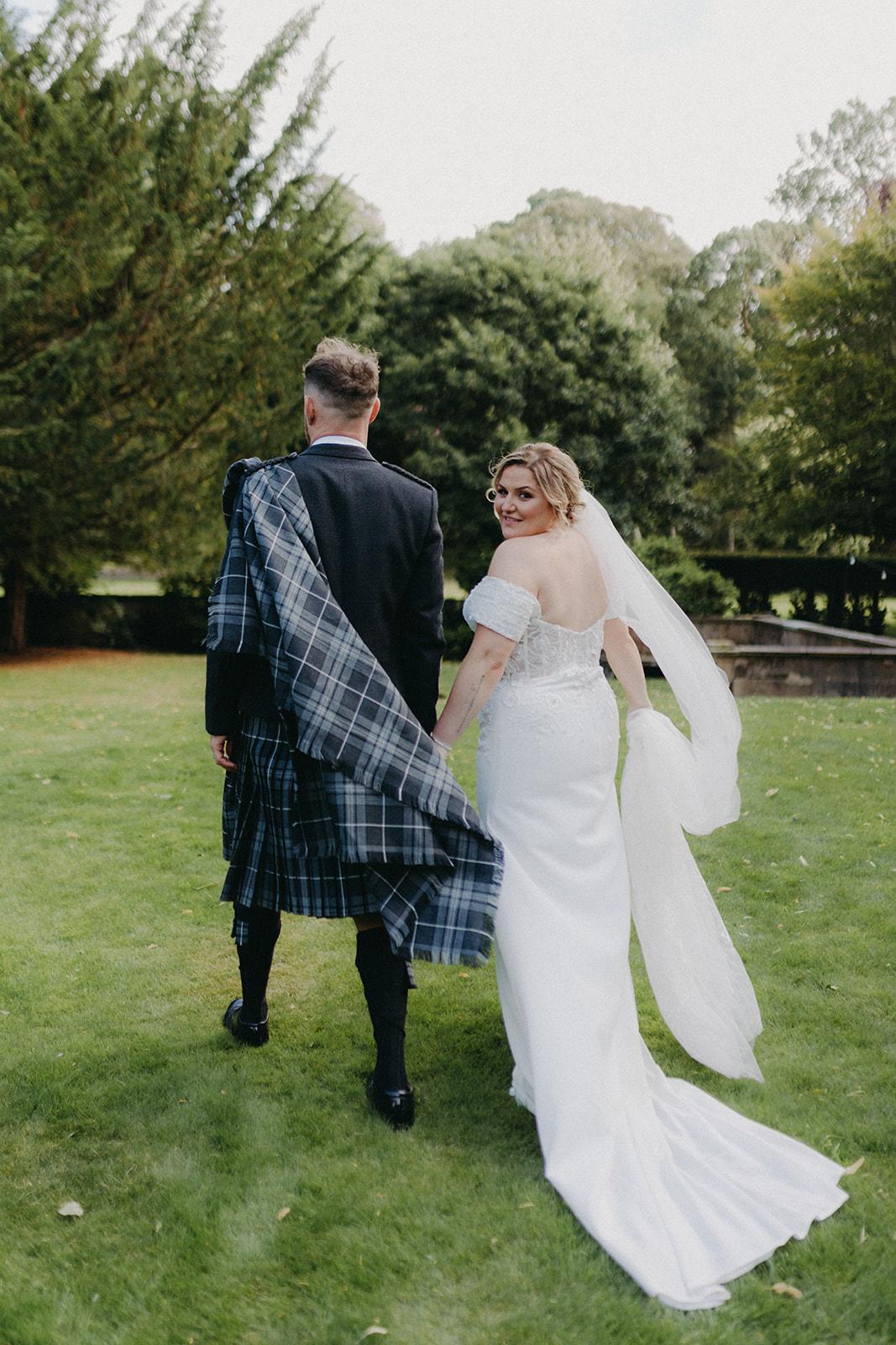 Off-the-shoulder crepe wedding gown with chapel-length train at a Scottish wedding
