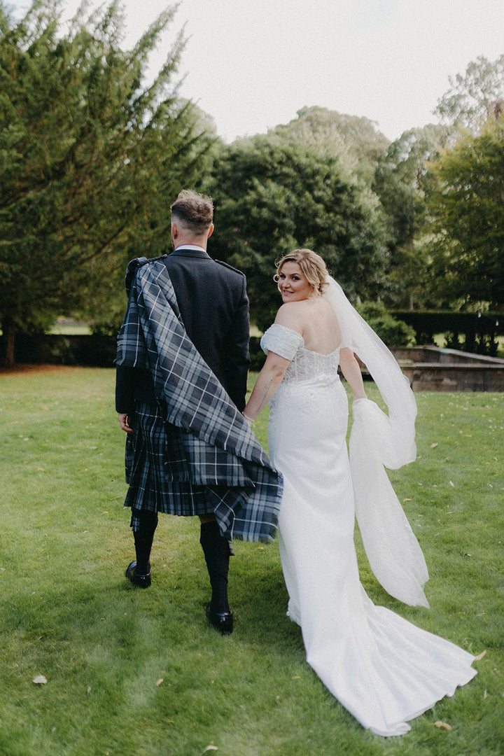 Off-the-shoulder crepe wedding gown with chapel-length train at a Scottish wedding