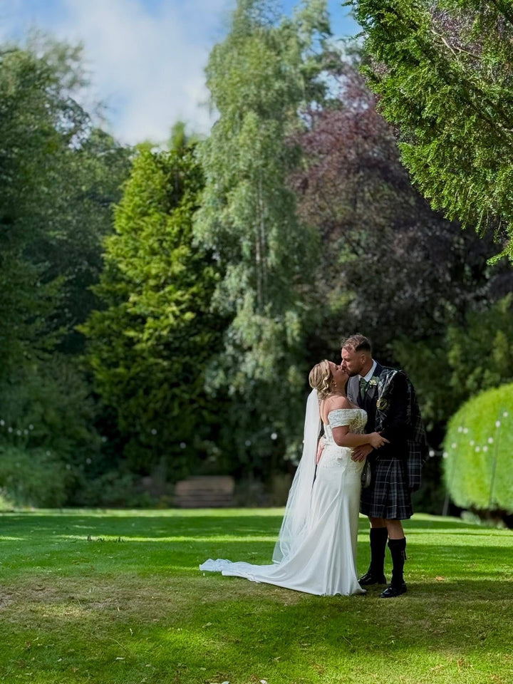 Full-length fitted crepe wedding dress with off-the-shoulder neckline and chapel train