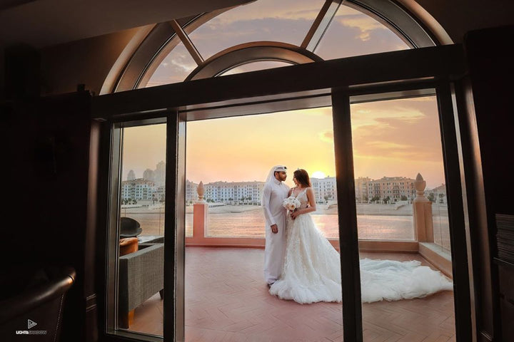 Luxury lace wedding gown with flowing bridal train photographed at sunset in Qatar